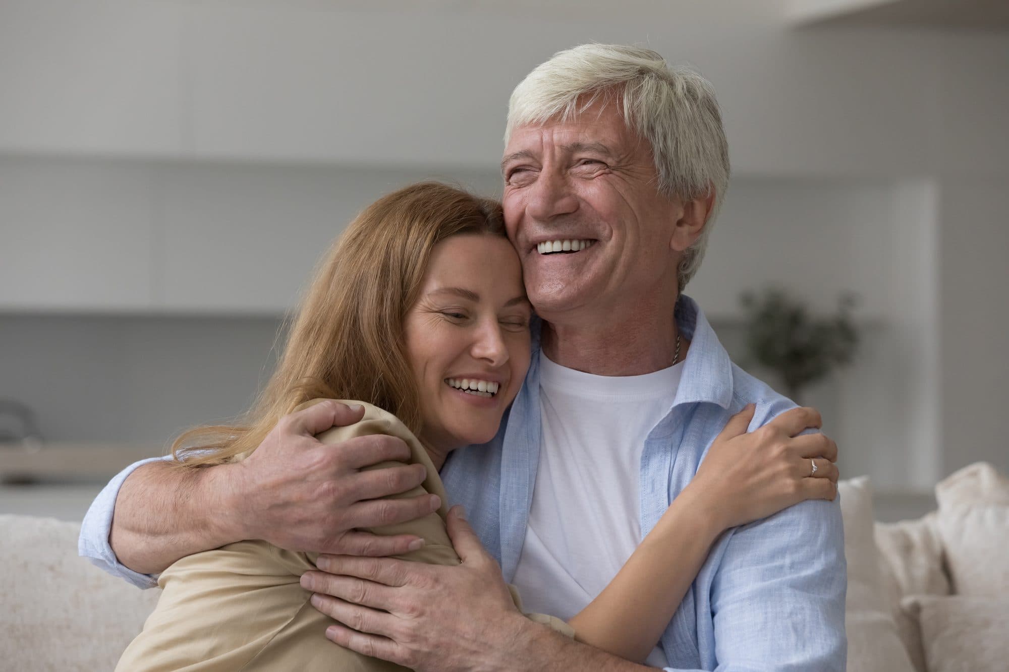 A daughter hugging her smiling father at home.